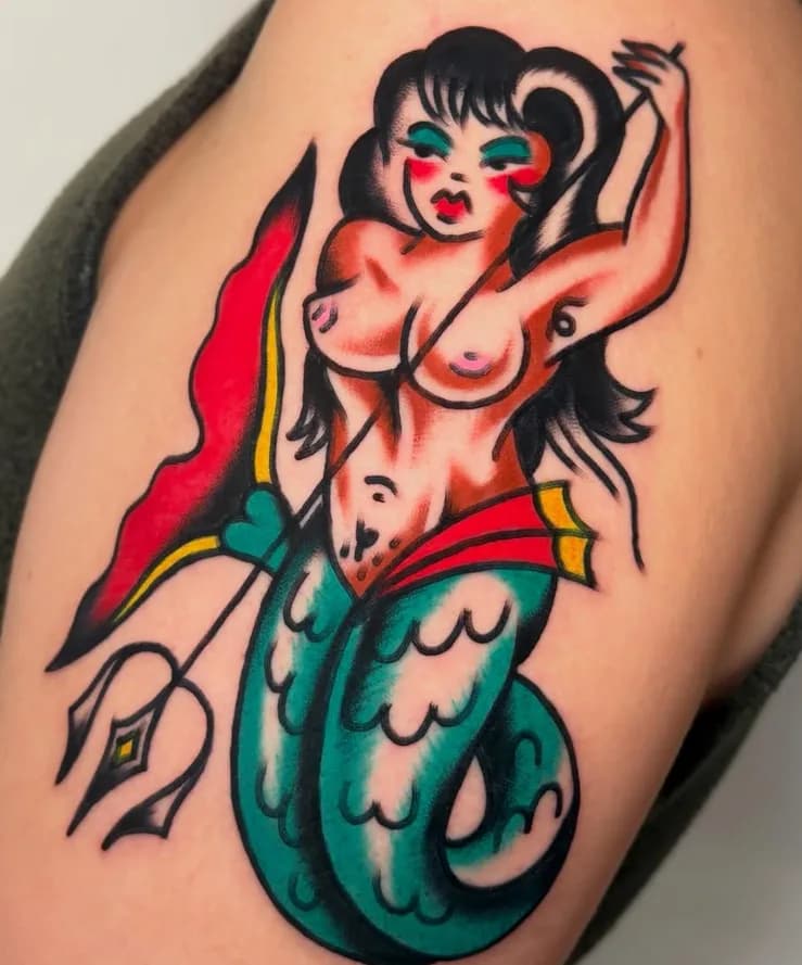 Traditional colorful mermaid tattoo with a spear, on the upper arm