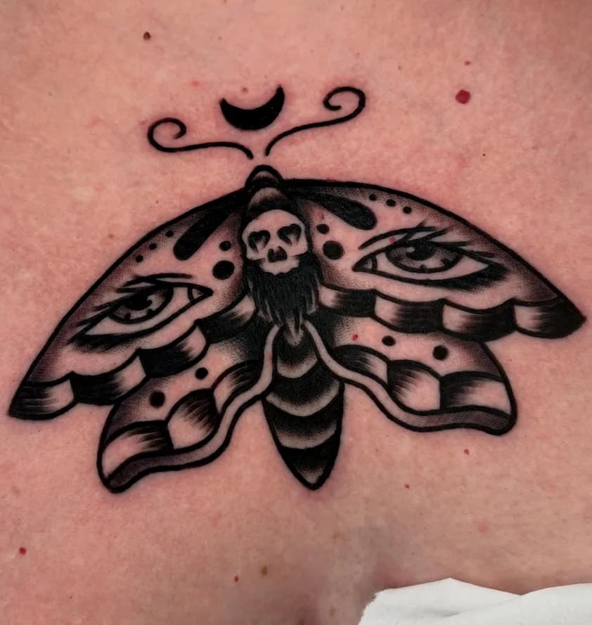 Black traditional death's-head moth tattoo with eyes on its wings, on the chest