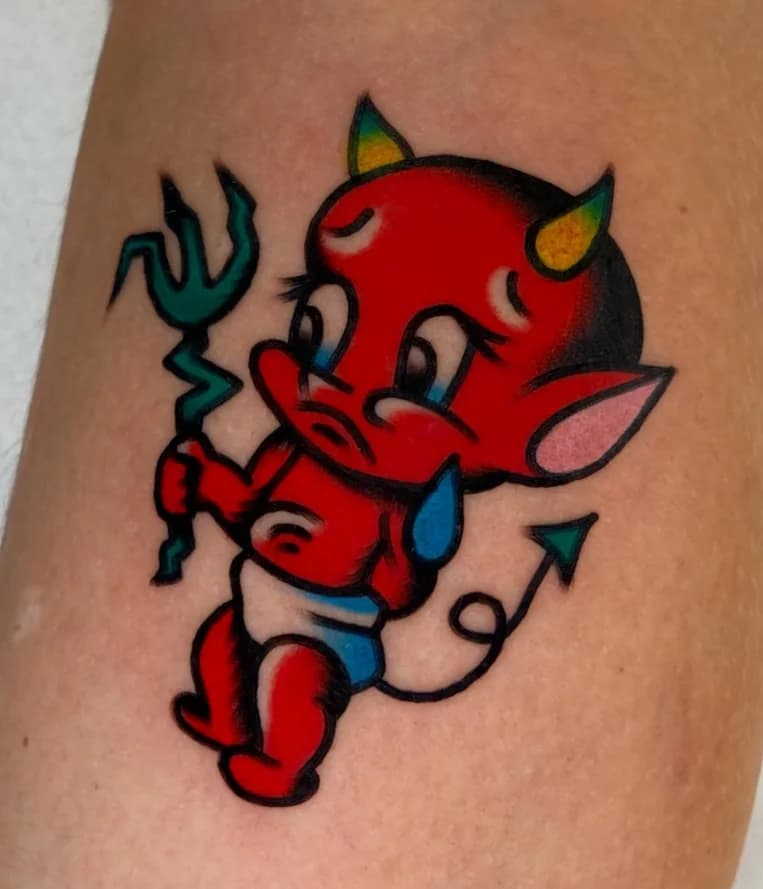 Traditional colorful red devil baby tattoo with a pitchfork, on the leg